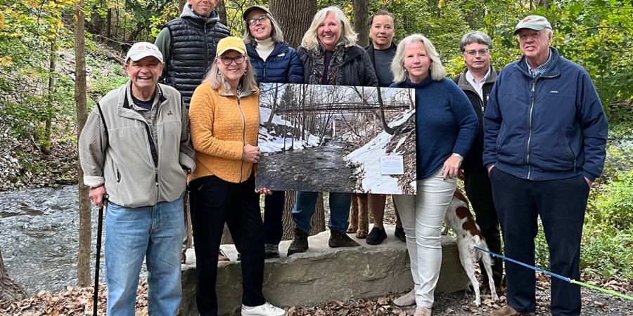 Members of Manchester Riverwalk hold a rendering of the new bridge that will go across the West Branch of the Battenkill in Manchester, VT.