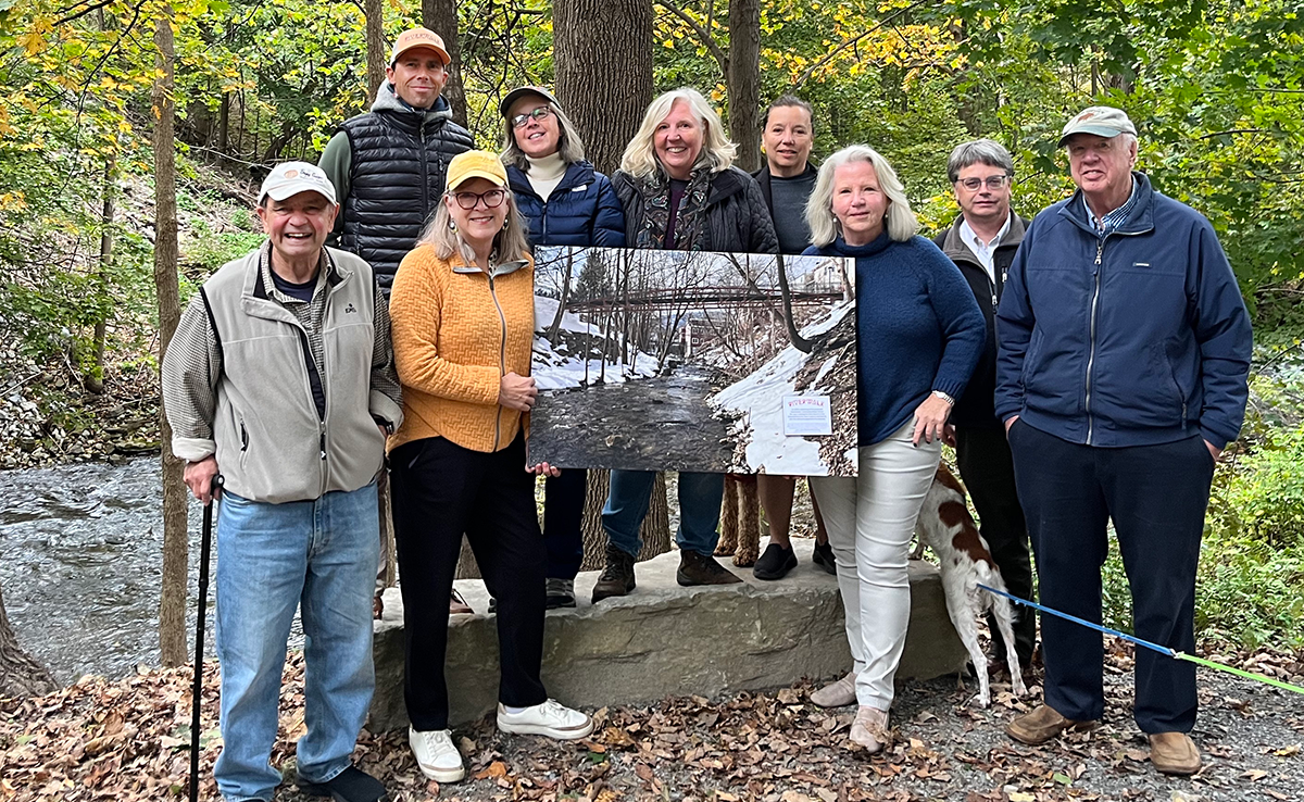 Members of Manchester Riverwalk hold a rendering of the new bridge that will go across the West Branch of the Battenkill in Manchester, VT.