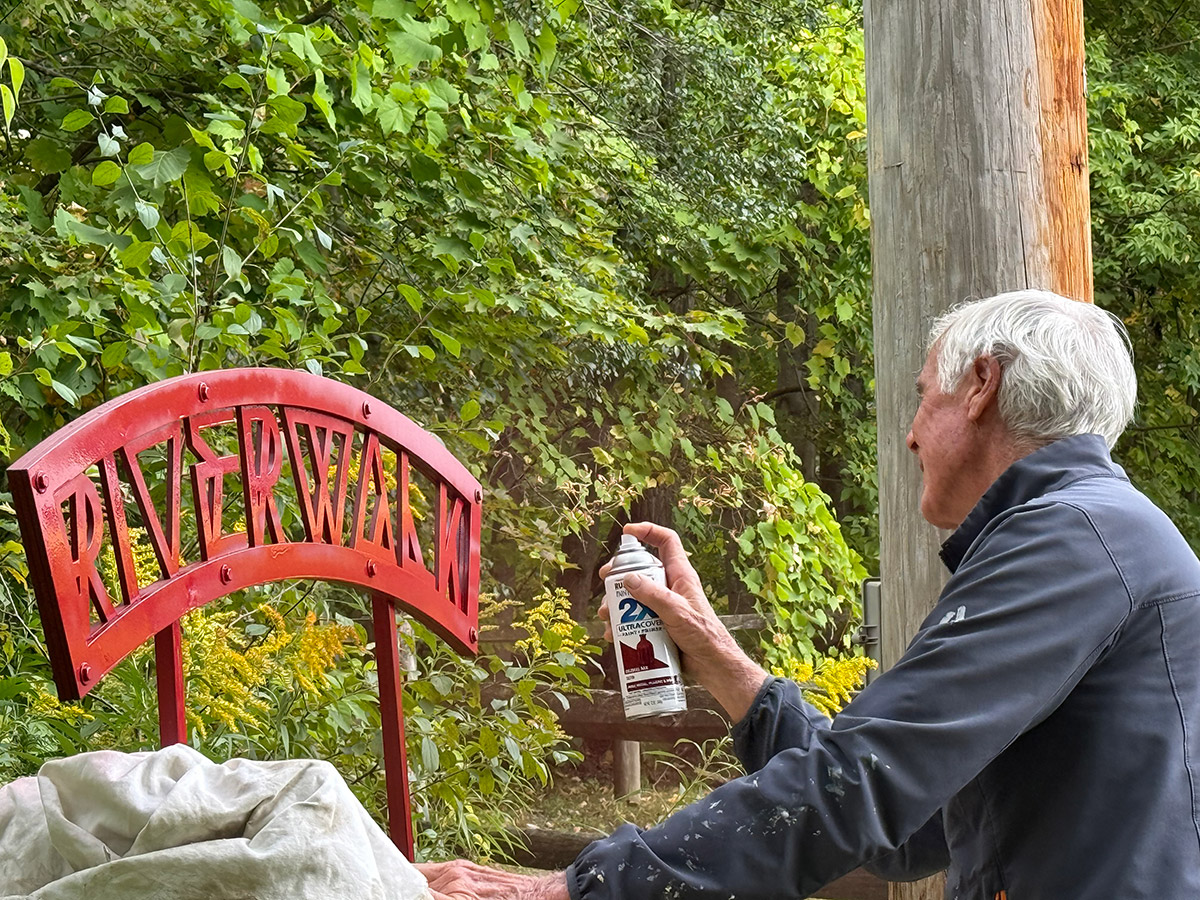 Jim Hand repainting the Riverwalk sign